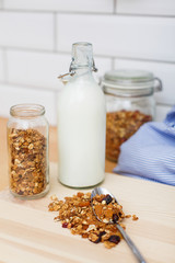 Granola on a spoon and milk glass bottle