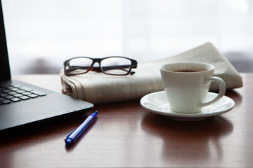 Newspaper with computer on table. Coffee break.