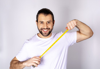 handsome man in white t-shirt on white background smiling, in his hands a ruler 