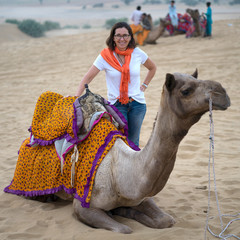 Happy woman standing near camel in desert, Kanoi, Jaisalmer, Rajasthan, India