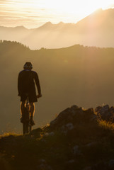 Mountainbiker auf Berggipfel im Sonnenuntergang.