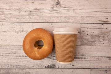 Take away coffee cup with bagel on wooden background