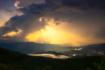 Sun rays from rain clouds and misty or fog flow or float along the ripple mountain 