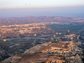 Colorful hot air balloons above Turkish National Park in Goreme. Panorama of Cappadocia landscape - multi colored balloons flying over mountain valley of ancient cave town Uchisar. March, 2019