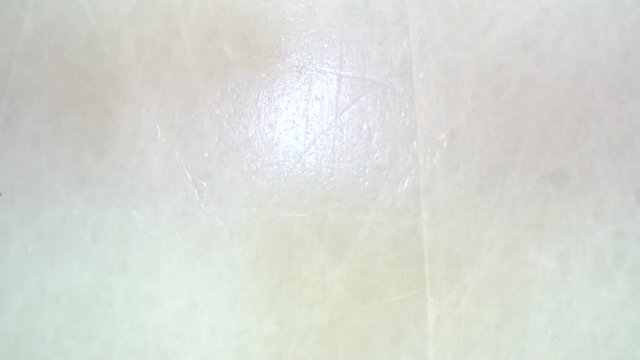 Hockey puck spins and falls on the ice in slow motion and stick hitting it, top view