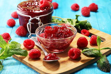 raspberry jam with fresh raspberries and mint. marmalade on spoon and jar on blue