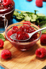 raspberry jam with fresh raspberries and mint. marmalade on spoon and jar on blue