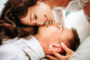 Obraz na płótnie Canvas Bride kissing the lying groom on meadow. Wedding session in park.