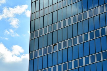 Fototapeta na wymiar Surface of glass building with the reflection of clouds