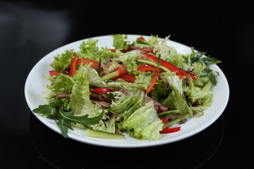 restaurant dish, green salad with cucumbers, red pepper, bacon and arugula, healthy food, close-up, for the menu