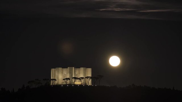 a shy moon rise behind Castel Del Monte
