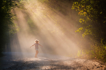 Young woman in the sun on a forest road. A girl is dancing in the forest. Bright emotion.
