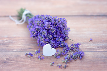 Fresh bouquet of lavender and a heart on brown wooden background.