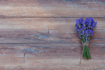 Fresh bouquet of lavender tied up with brown hemp on brown wooden background.
