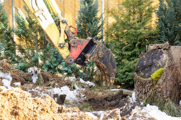 An excavator works in the garden, removing a root