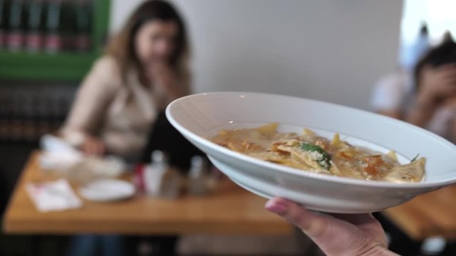 Tracking shot of plate carried by waitress in the restaurant. Close up shot