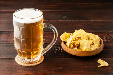 glass of cold frothy lager beer and potato chips plate