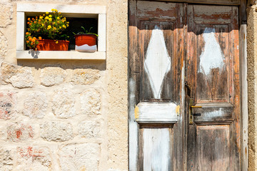 Authentic house with a stone wall and a beautiful door and flowerpots with flowers at the entrance, in minimal style, bright colors, background. Montenegro