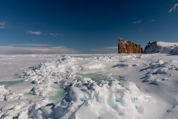 Fototapeta na wymiar Winter sea ice with the majestic Percé Rock in the background.