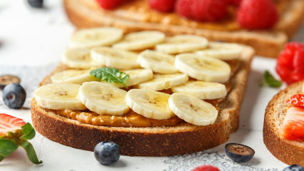 Peanut butter sandwiches with fresh strawberry, blueberry, raspberry and banana whole meal toasts.