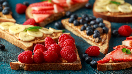 Peanut butter sandwiches with fresh strawberry, blueberry, raspberry and banana whole meal toasts.