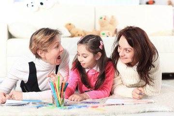 Fototapeta premium little girl draws with her mother and grandmother
