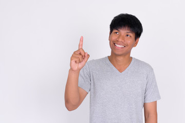 Portrait of happy young Asian man thinking and pointing up
