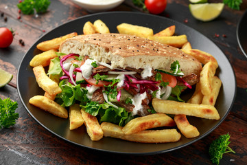 Doner kebab, fried lamb meat with vegetables, fries and garlic sauce in turkish bread