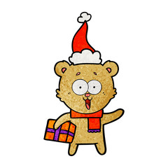 laughing teddy  bear with christmas present wearing santa hat
