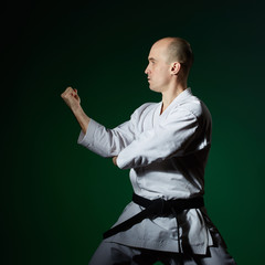 With a black belt, the athlete does formal karate exercises on a dark green background