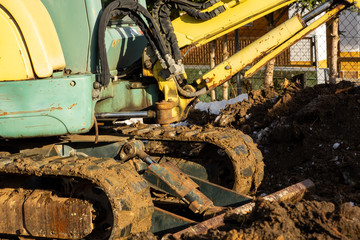 Fototapeta na wymiar An excavator works in the garden, removing a root