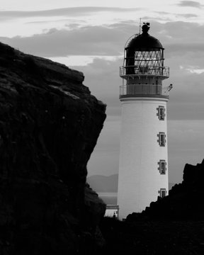 Close up of Rua Reidh lighthouse along cliff in Scotland, in black and white.