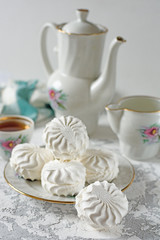 Marshmallow on a plate with a kettle close up on a light background