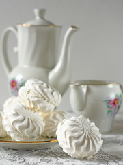 Marshmallow on a plate with a kettle close up on a light background
