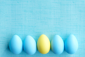 Blue and yellow Easter eggs on blue texture background with copy space for holiday graphic.