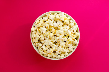 plate with popcorn on pink paper background
