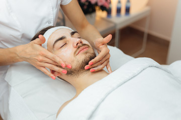 Obraz na płótnie Canvas Unshaven man having cosmetic mask care in spa salon, side, top view - Image