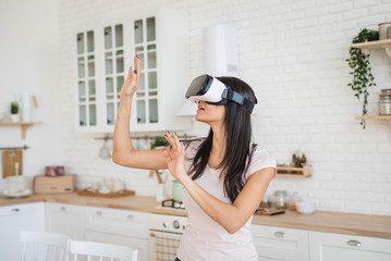 Young woman in VR glasses in kitchen at home - 253833246