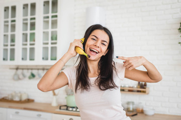 Attractive woman is holding banana like a mobile phone, funny concept