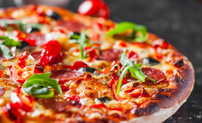 Pepperoni Pizza with Mozzarella cheese, salami, Tomatoes, olive, pepper, Spices and Fresh arugula. Italian pizza on dark background