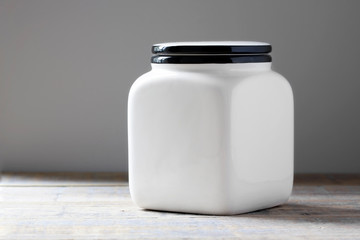 Mockup of a white ceramic canister on a wooden table.