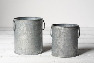 Mockup of two metal containers on a white wooden table.