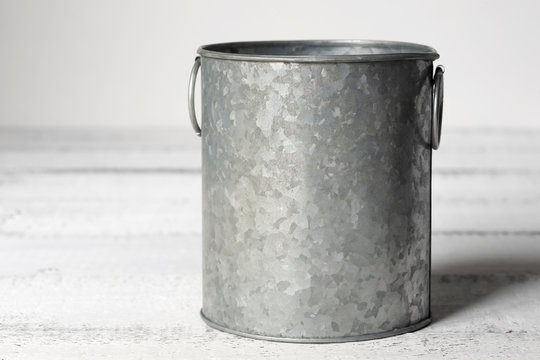 Mockup of a single metal container on a white wooden table.