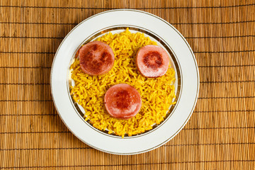 yellow rice on a plate with fried sausage.