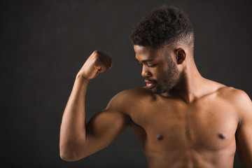 Obraz premium handsome african man on black background showing his muscles