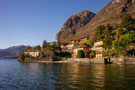 Italy, Menaggio, Lake Como, a small boat in a body of water with a mountain in the background