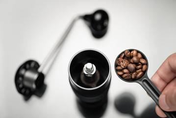A man puts coffee grains in a coffee grinder