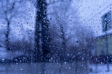 Background image of rain drops on a glass window. Blue tone