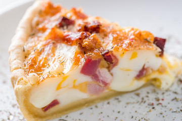 piece of quiche on a white plate served with spices