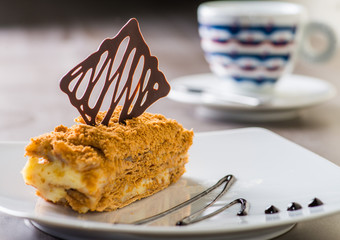 piece of cake served on a white plate with a cup of coffee